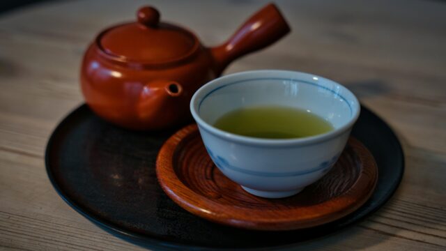 Traditional Japanese teapot and cup of green tea on a wooden table.
